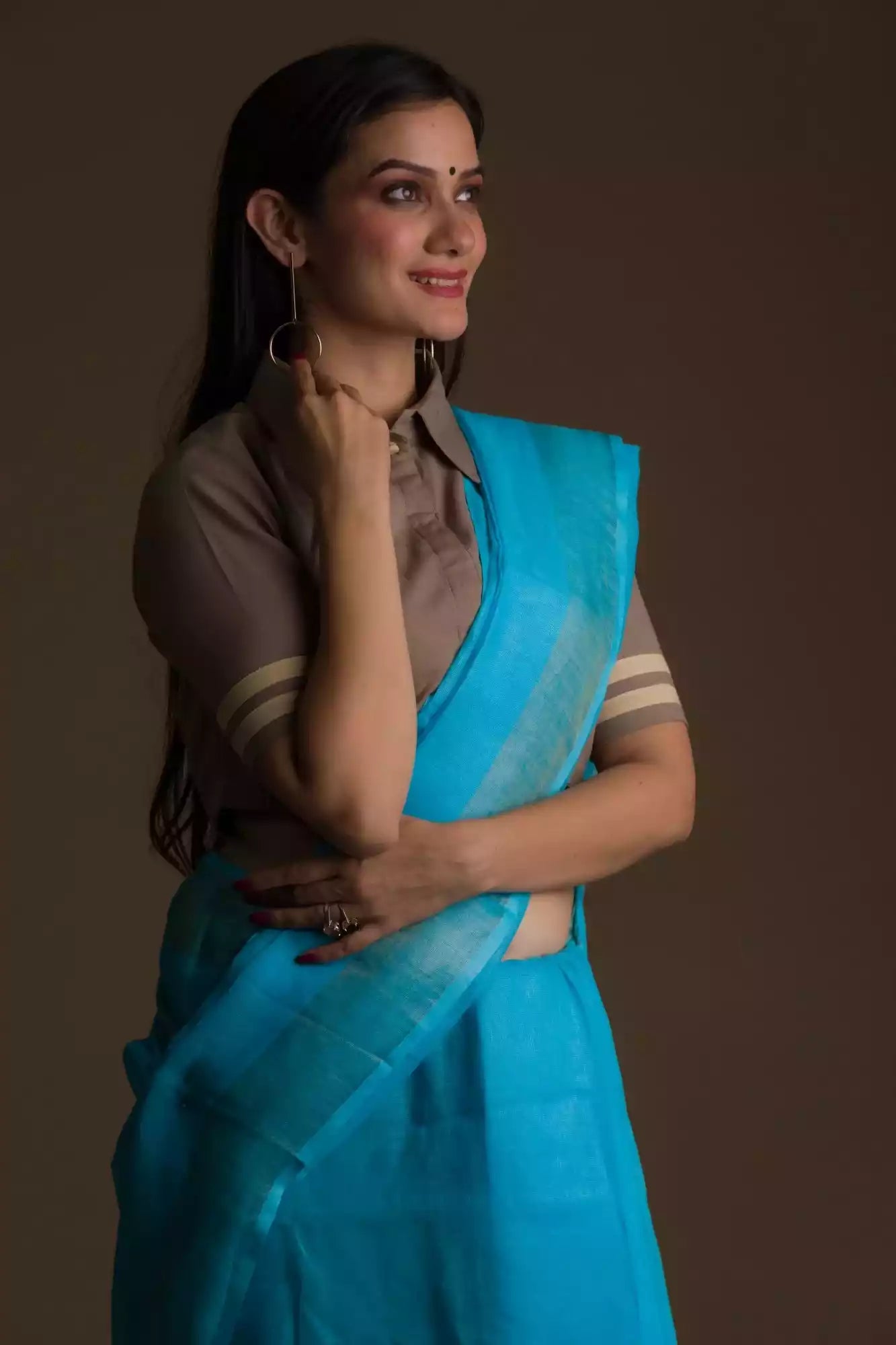 side view of a  woman wearing a cyan saree with brown blouse 