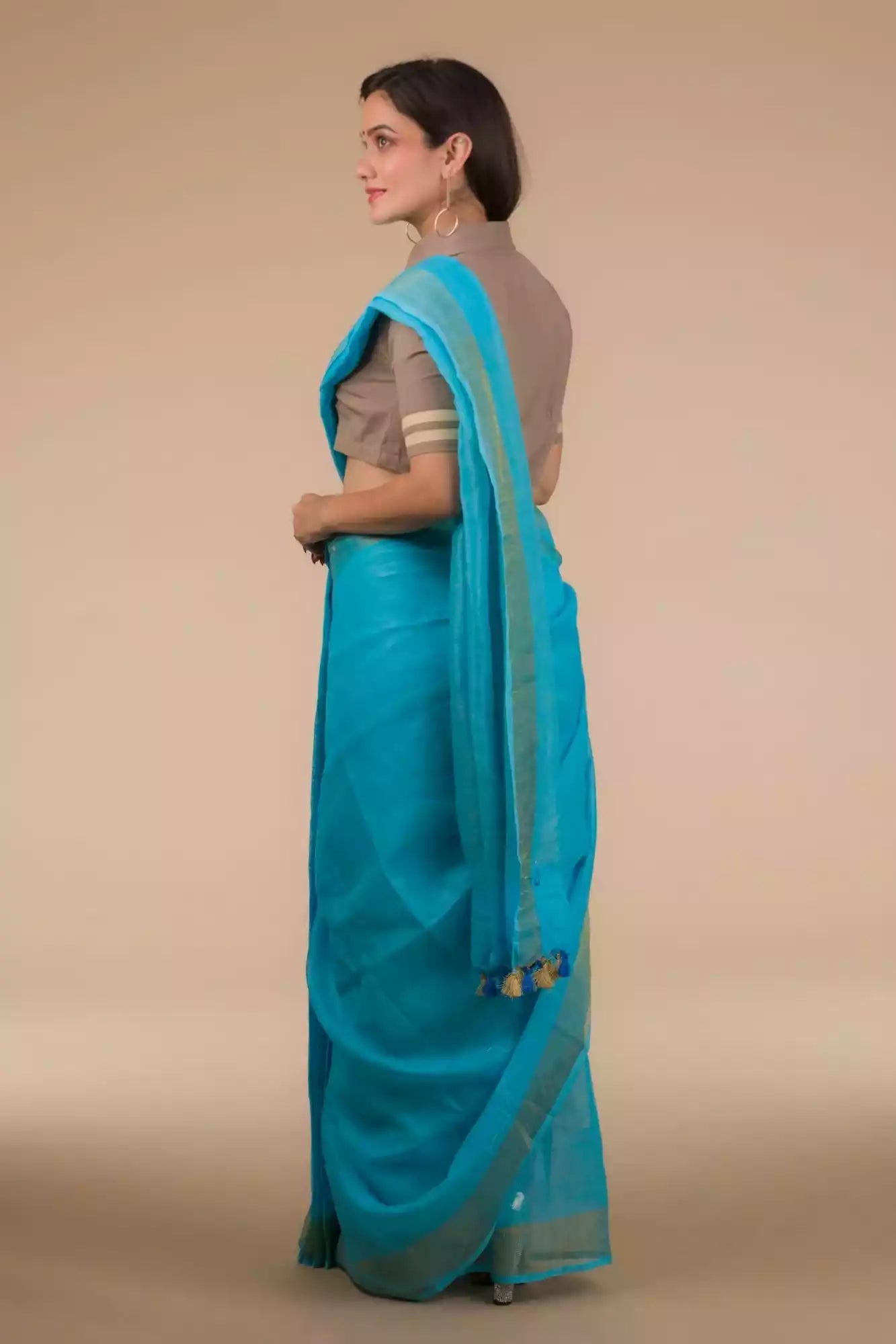 back view of a woman wearing a cyan saree with brown blouse and heels