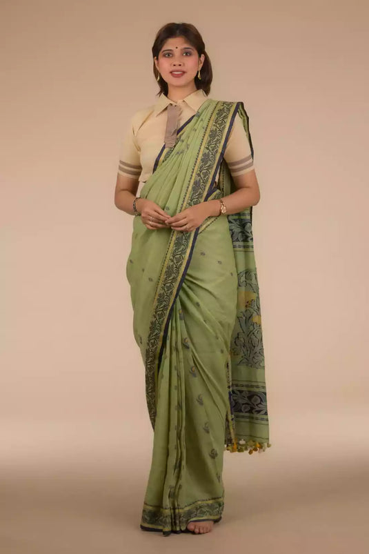 A lady in Myrtle Linen Saree in Olive Green, womens workwear standing against a beige background looking sideways