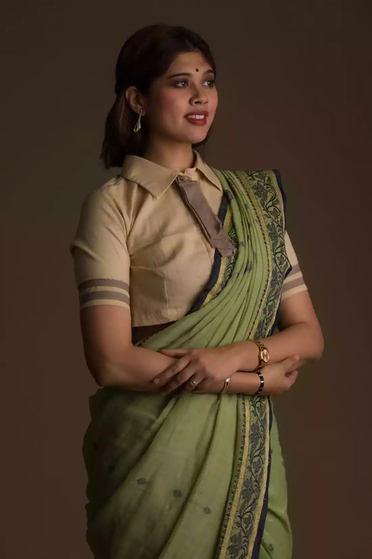 A lady in Myrtle Linen Saree in Olive Green, womens workwear standing against a tan background sidewaysn