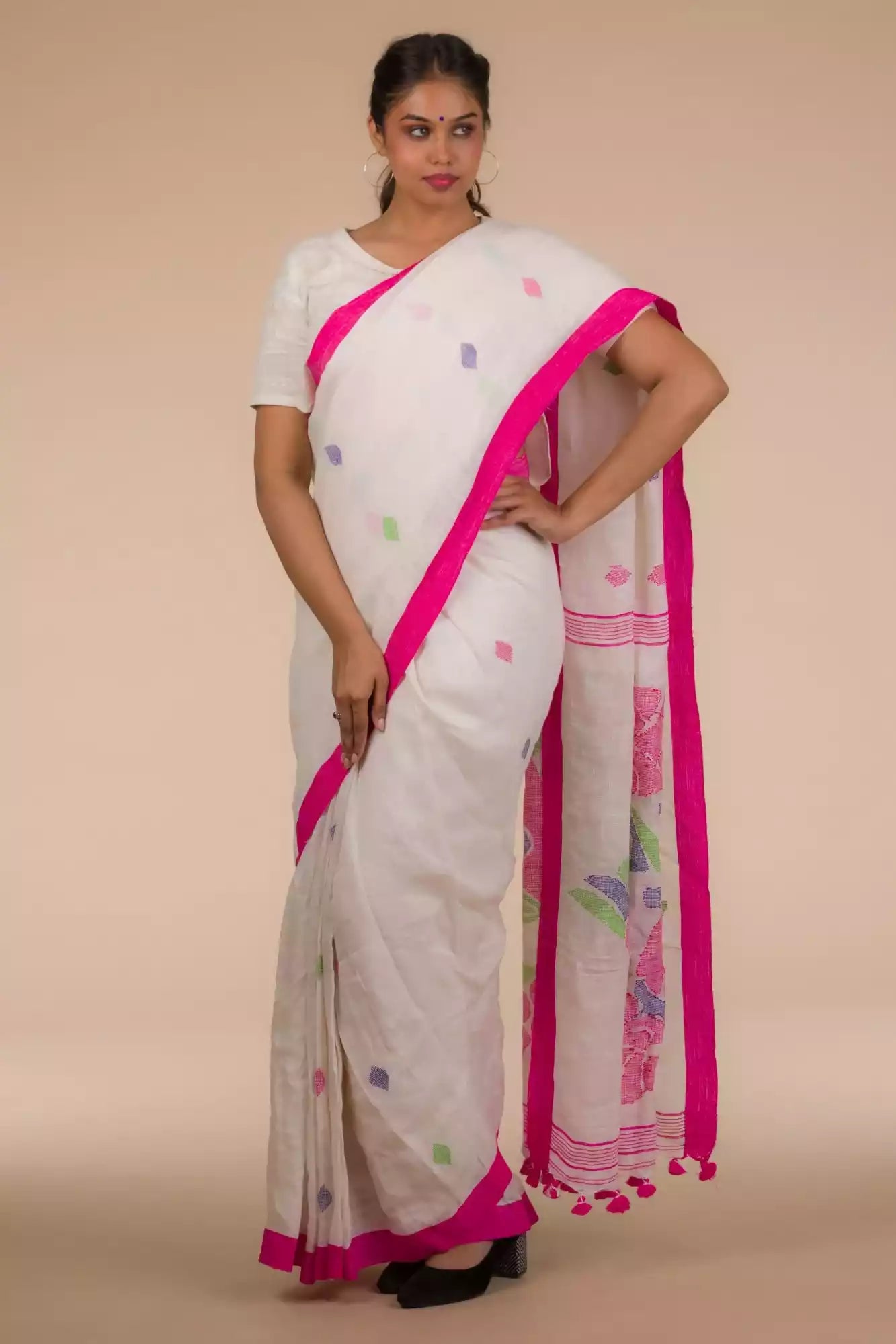 front view of a woman wearing a white saree with pink polka dot work on it and the bottom half