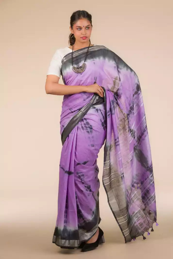 a beautiful woman wearing a Purple Shibori In Cotton Viscose Saree, women workwears is posed in front of a tan background
