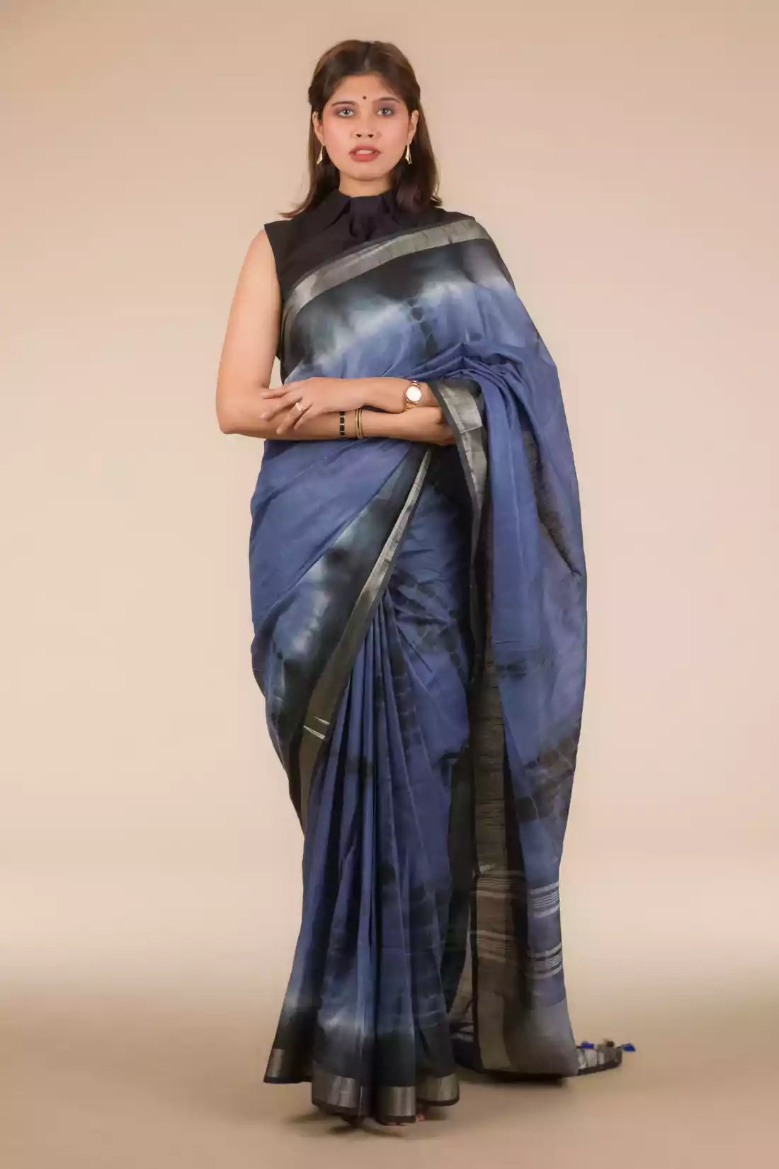 a beautiful woman wearing a Grey Shibori In Cotton Viscose Saree, women workwears is posed in front of a tan background