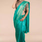 a beautiful woman wearing a Sea green In Tussar by Munga Saree, women workwears is posed in front of a tan background