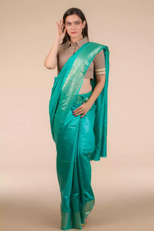 a beautiful woman wearing a Sea green In Tussar by Munga Saree, women workwears is posed in front of a tan background