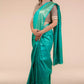 A lady in Sea green In Tussar by Munga Saree standing against a beige background