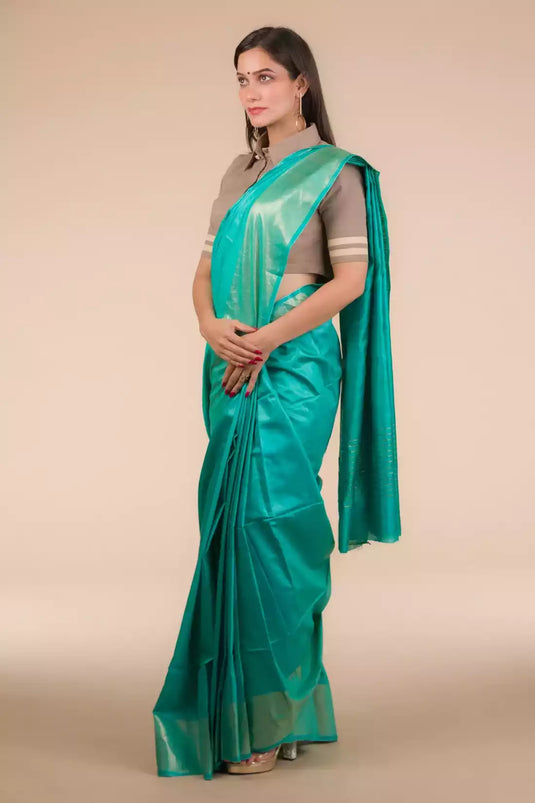 A lady in Sea green In Tussar by Munga Saree standing against a beige background