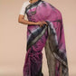 a beautiful woman wearing a Shibori In Cotton Viscose Saree, women workwears is posed in front of a tan background