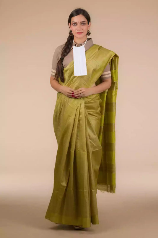 This a photo of beautiful woman wearing a Olive Green Plain In Pure Tussar Saree, women workwears is posed in front of a tan background