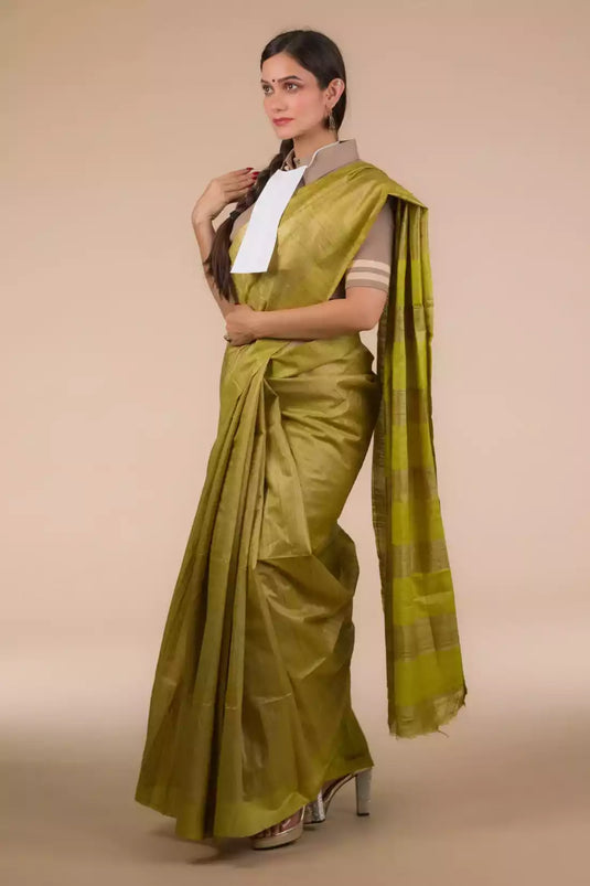 A lady in Olive Green Plain In Pure Tussar Saree, womens workwear standing against a beige background