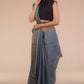 an image of a woman in a grey saree with dark colored sleeveless blouse and a belt around her waist