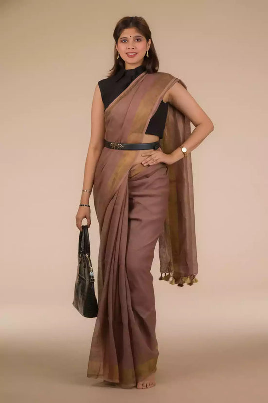 a woman in a chestnut brown in pure linen saree standing which women workwear in front of a beige backdrop