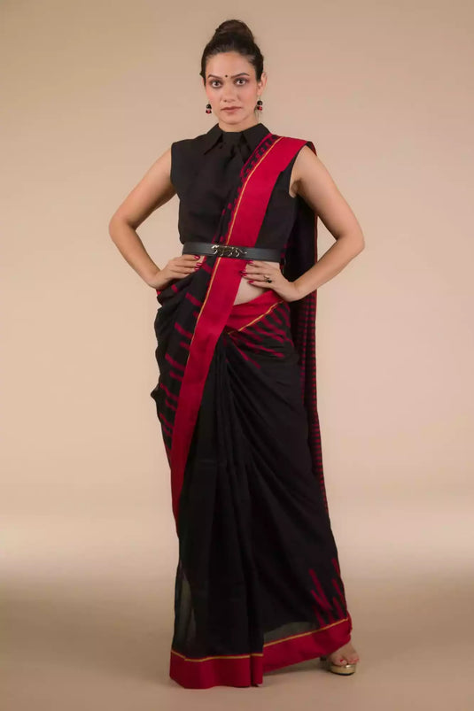a beautiful woman wearing a red stripes and black saree is posed in front of a tan background