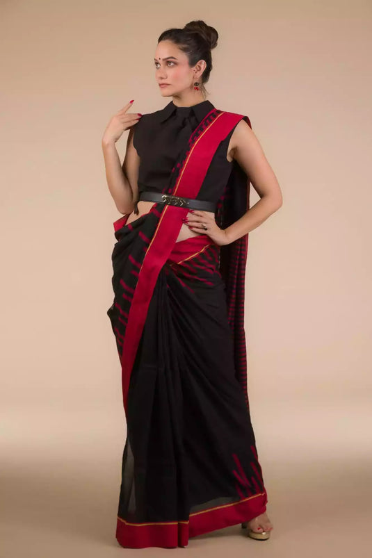 a woman wearing a red and black saree is posed in front of a tan background