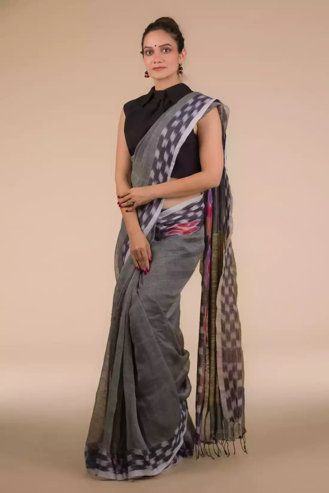 a woman in Grey with ikkat border In Pure Cotton Saree, a business formal for women  standing in front of a beige backdrop