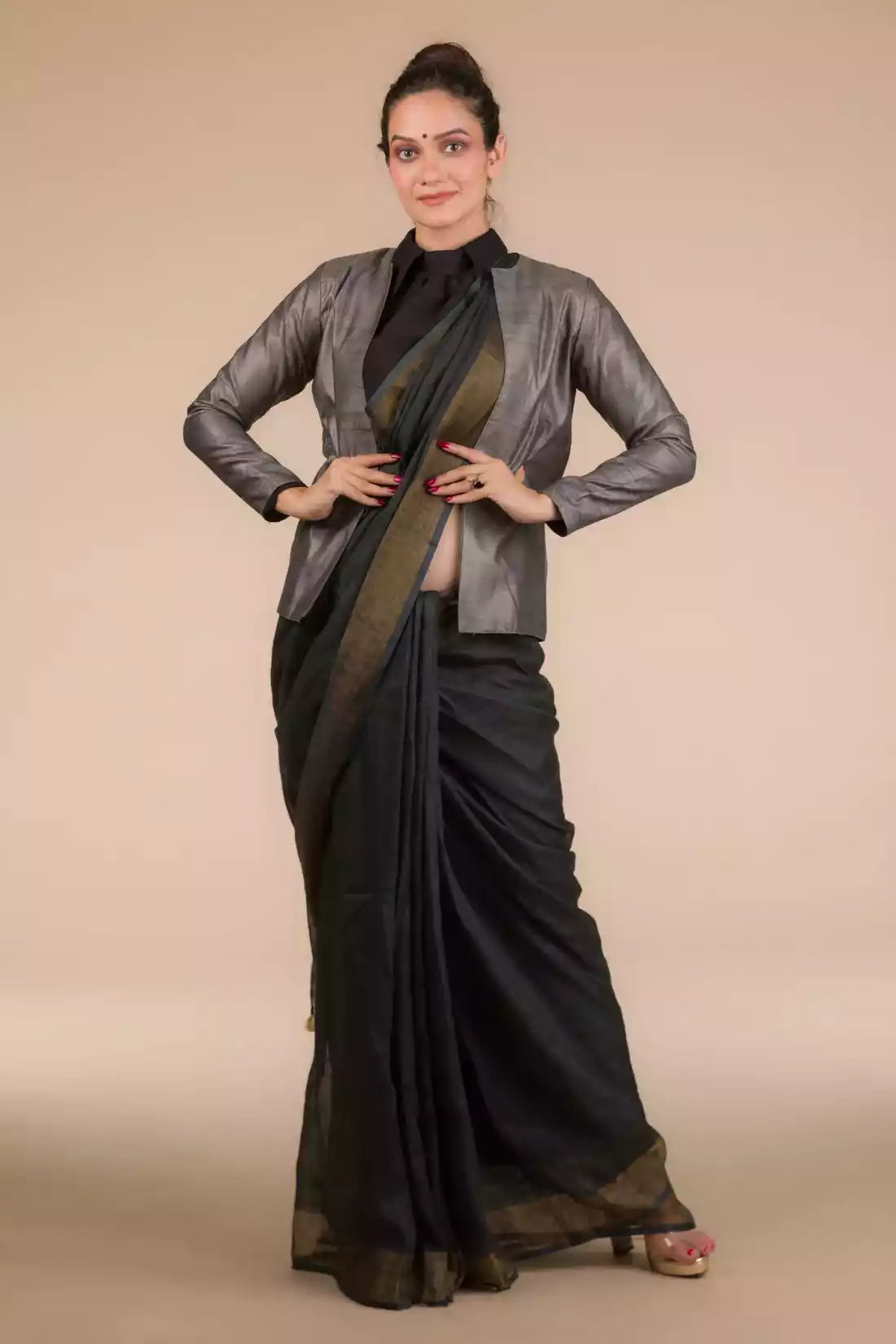 A lady in Indy Ebony Linen Saree in black, womens workwear standing against a tan background looking  down