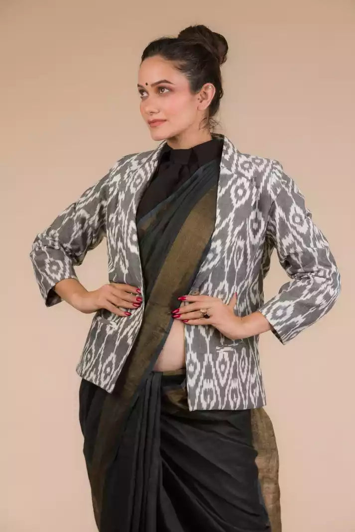 A lady in Indy Ebony Linen Saree in black, womens workwear standing against a beige background looking sideways