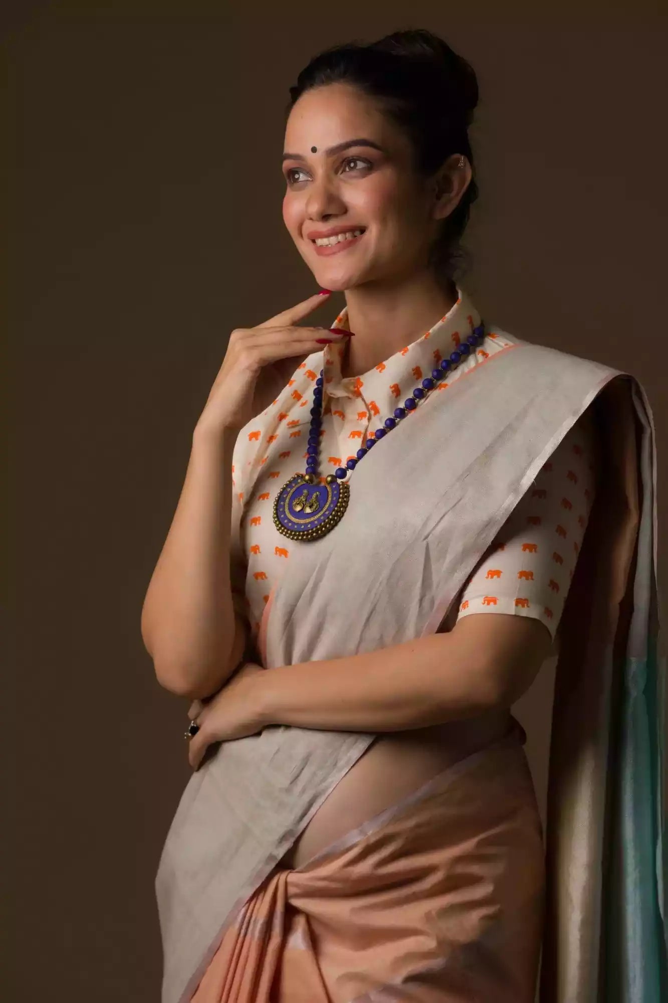 closure look of a beautiful woman with a bun wearing a multicolor pastel saree with multicolor blouse and blue jewellery