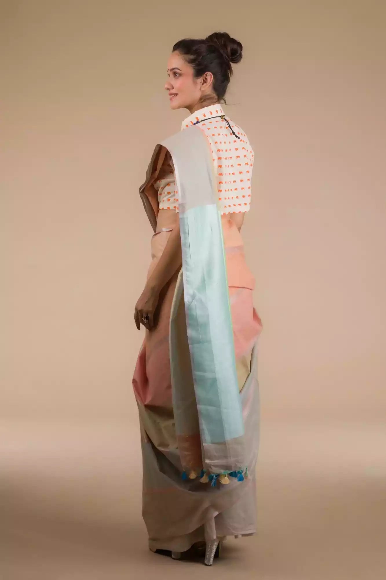 back view of a beautiful woman with a bun wearing a multicolor pastel saree with multicolor blouse 